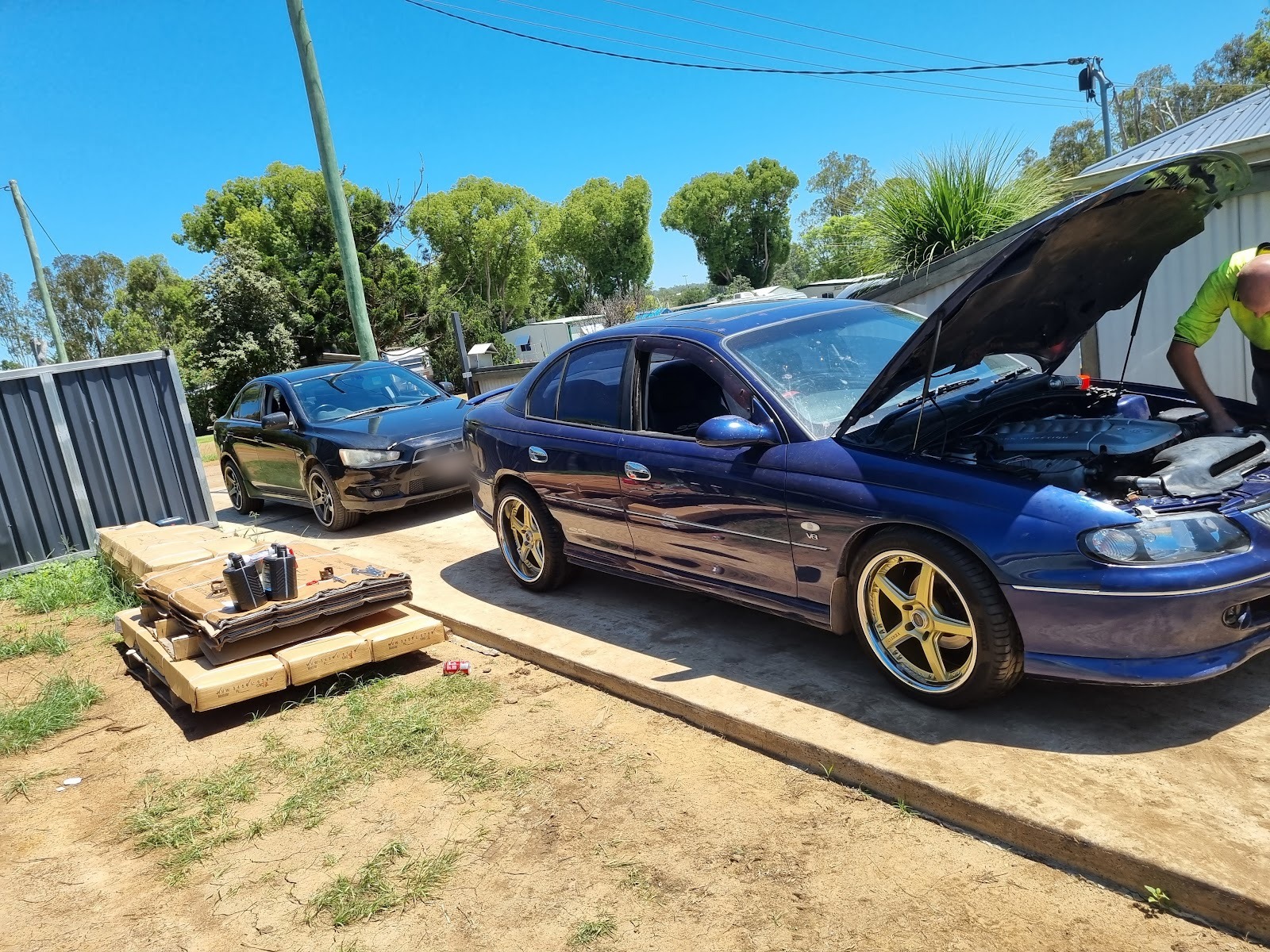 Blue Holden Commodore with the bonnet up being worked on in the yard