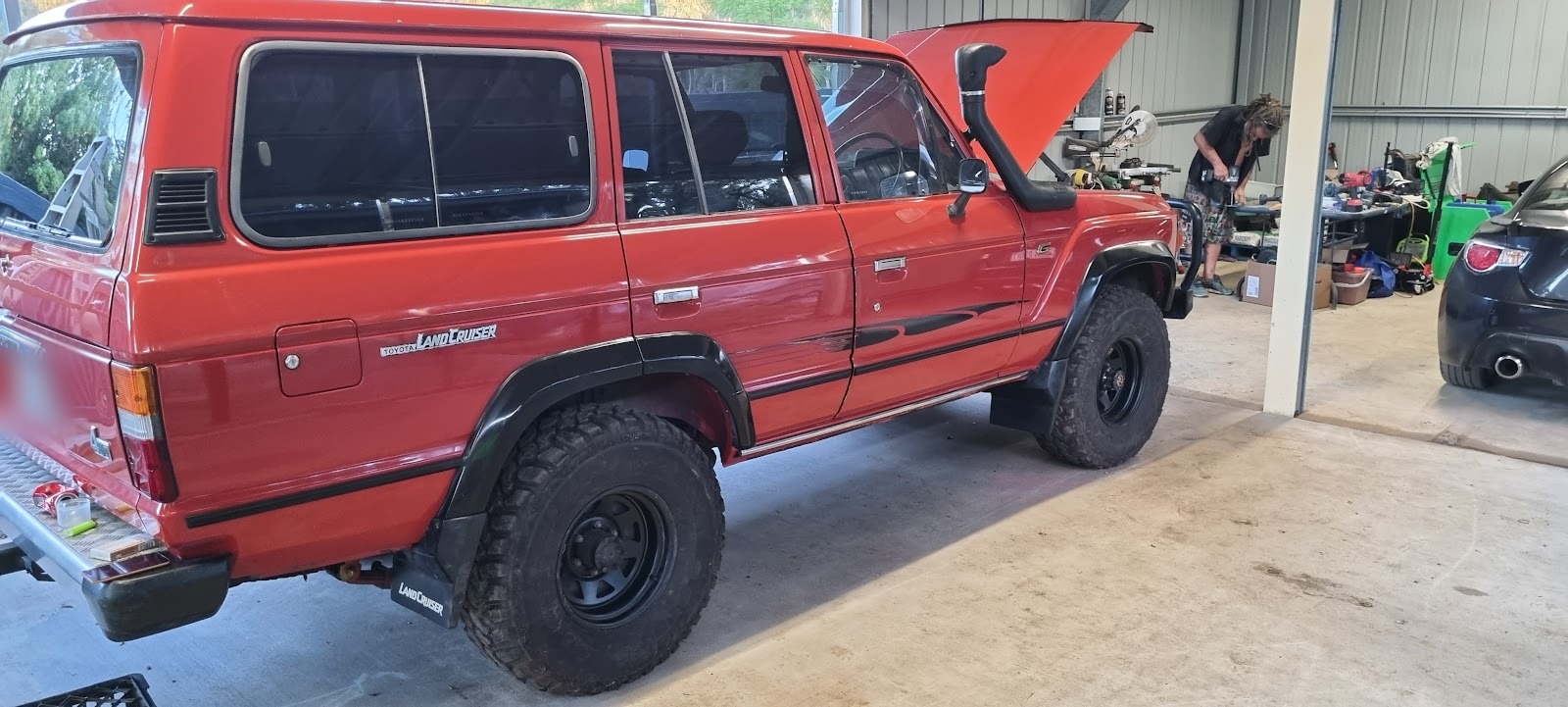 Red Toyota LandCruiser 60 Series with a snorkel and black steel wheels in the workshop