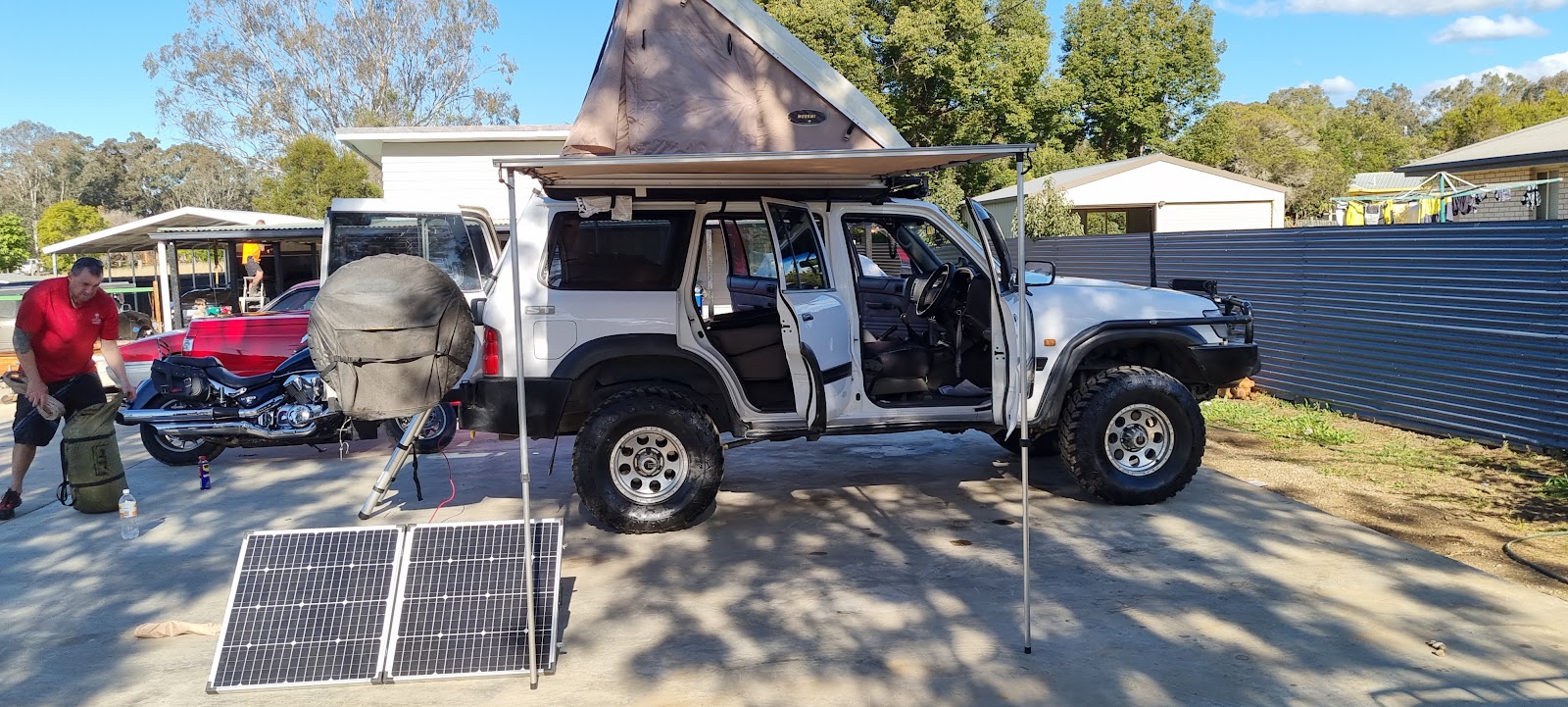 Touring 4WD fitted with a rooftop tent, awning and solar panels in the yard