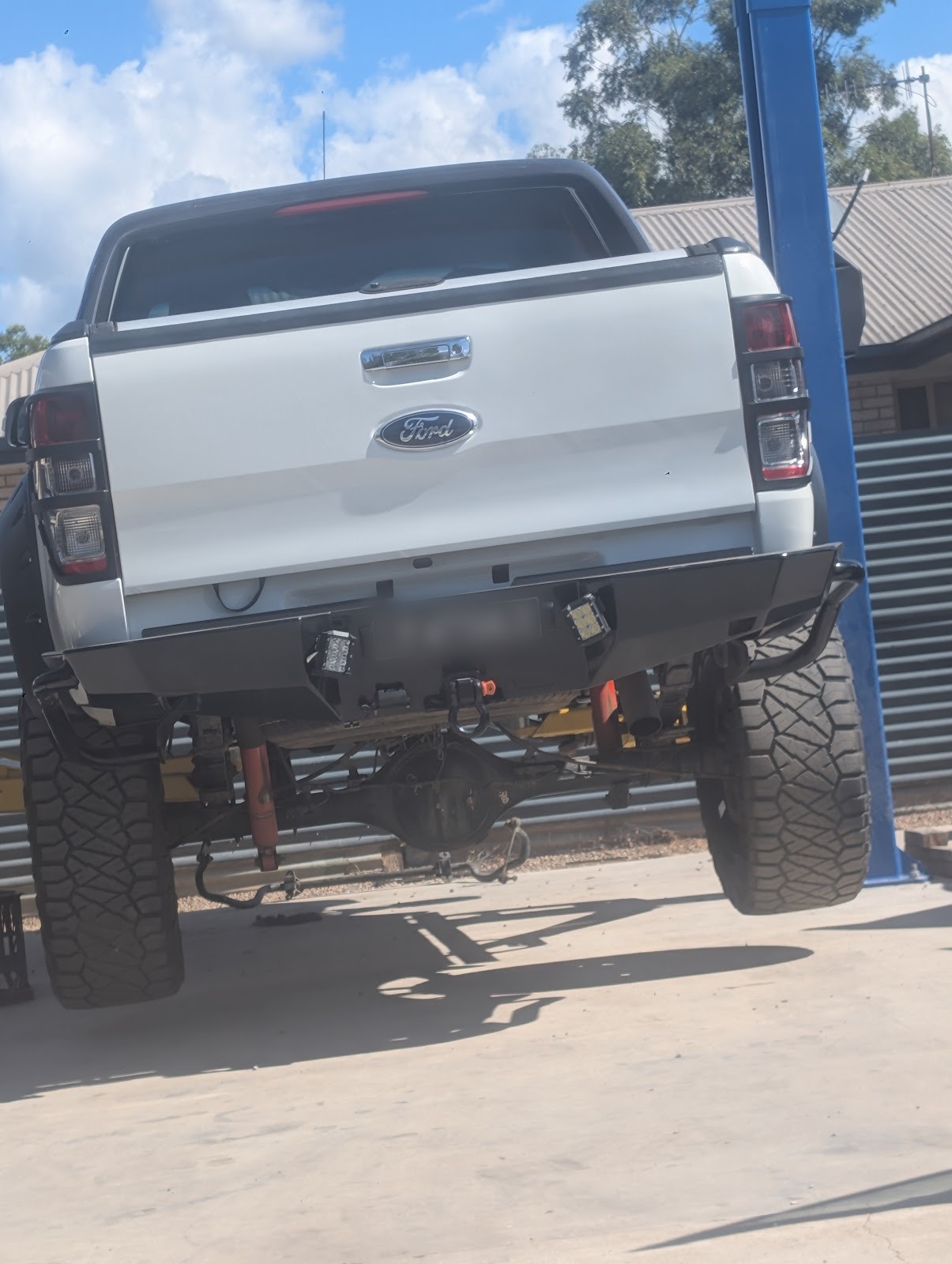 Lifted white Ford Ranger up on the workshop hoist